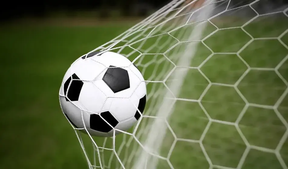 A black and white football hitting the back of a net.